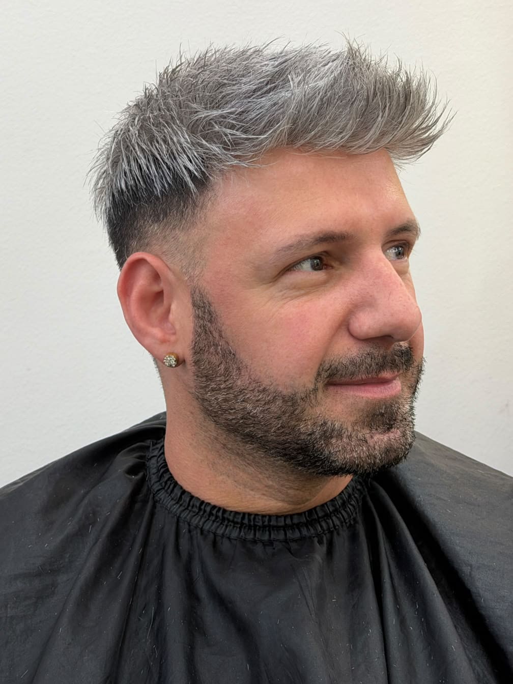 Pablo Castro de tres cuartos con el sistema capilar: pelo gris plateado, corto y levantado.