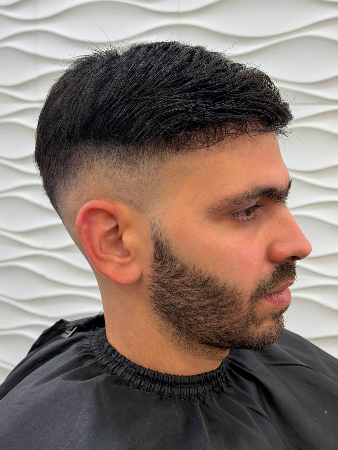 Daniel Sanchez de perfil con el sistema capilar: pelo oscuro y corto, peinado hacia atrás, con los costados rebajados.